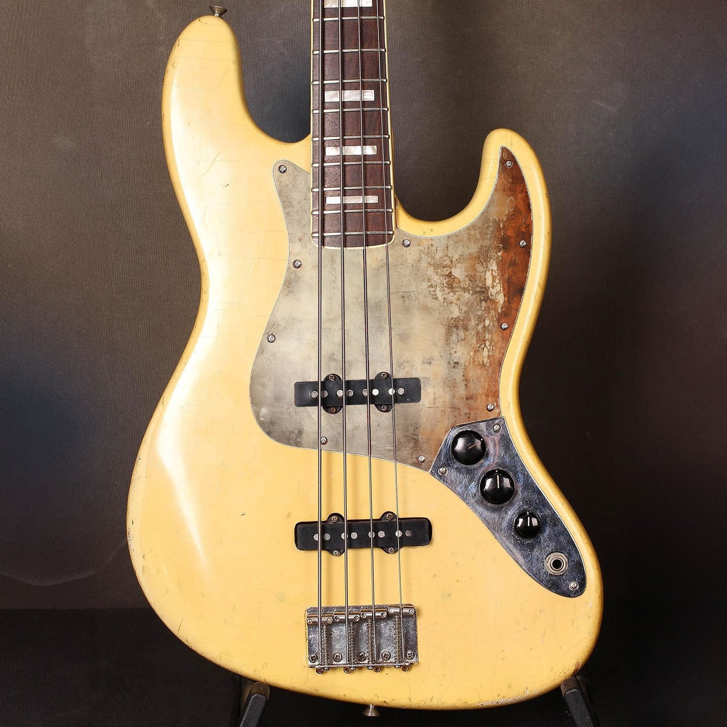 Egyedi Fender Jazz Bass gitár koptató rozsdásodó fémhatással, fakó bézs tónusokkal és mély narancsos oxidált foltokkal