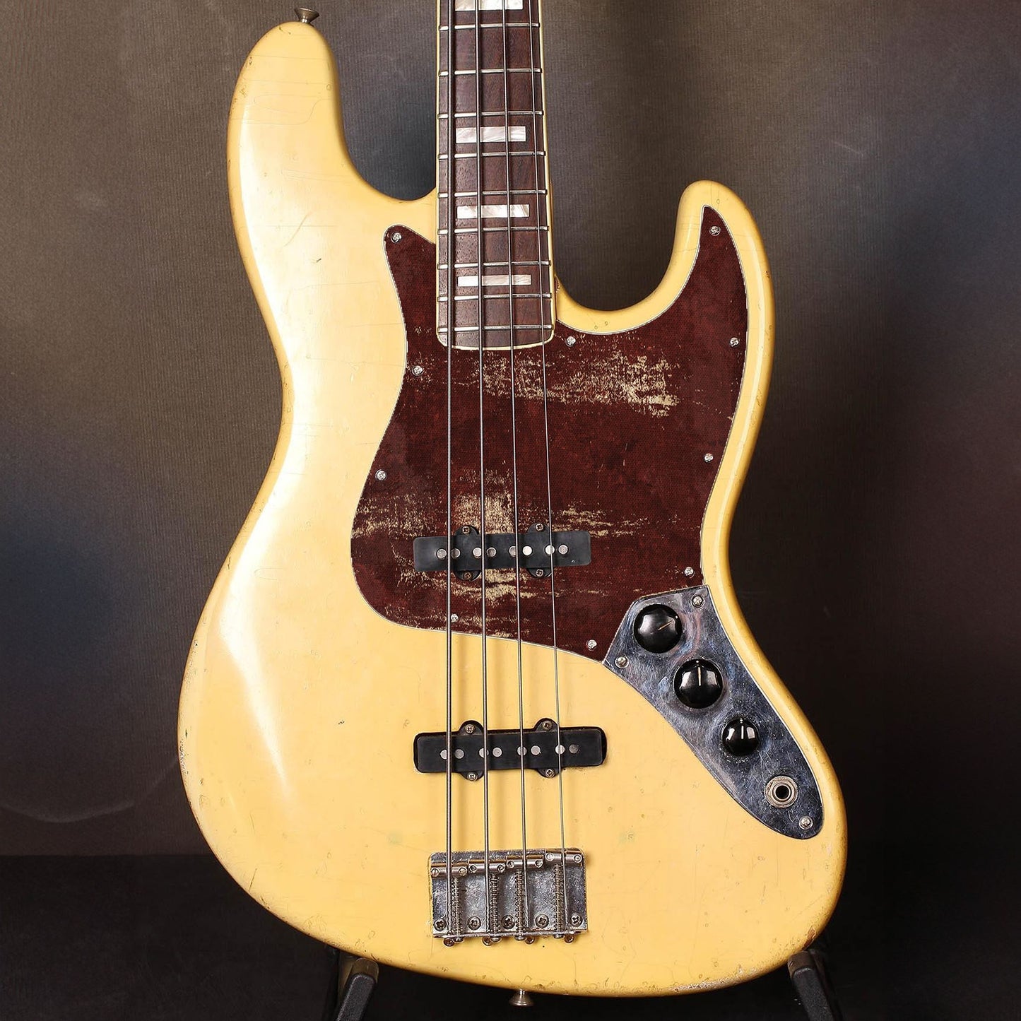 Egyedi Fender Jazz Bass gitár koptató bordó tónusokkal és patinás arany mintázattal, durva textúrával és markáns megjelenéssel