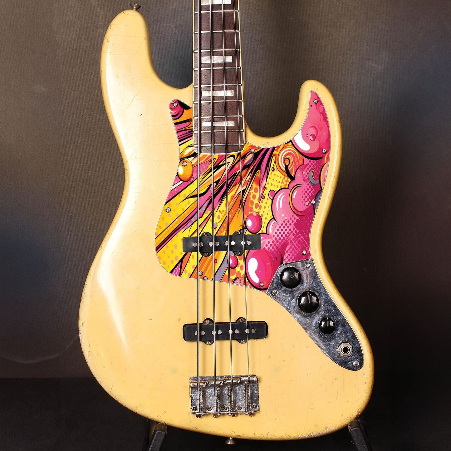 Egyedi Fender Jazz Bass gitár koptató színes pop-art stílusban, energikus sárga és rózsaszín árnyalatokkal és modern mintázattal
