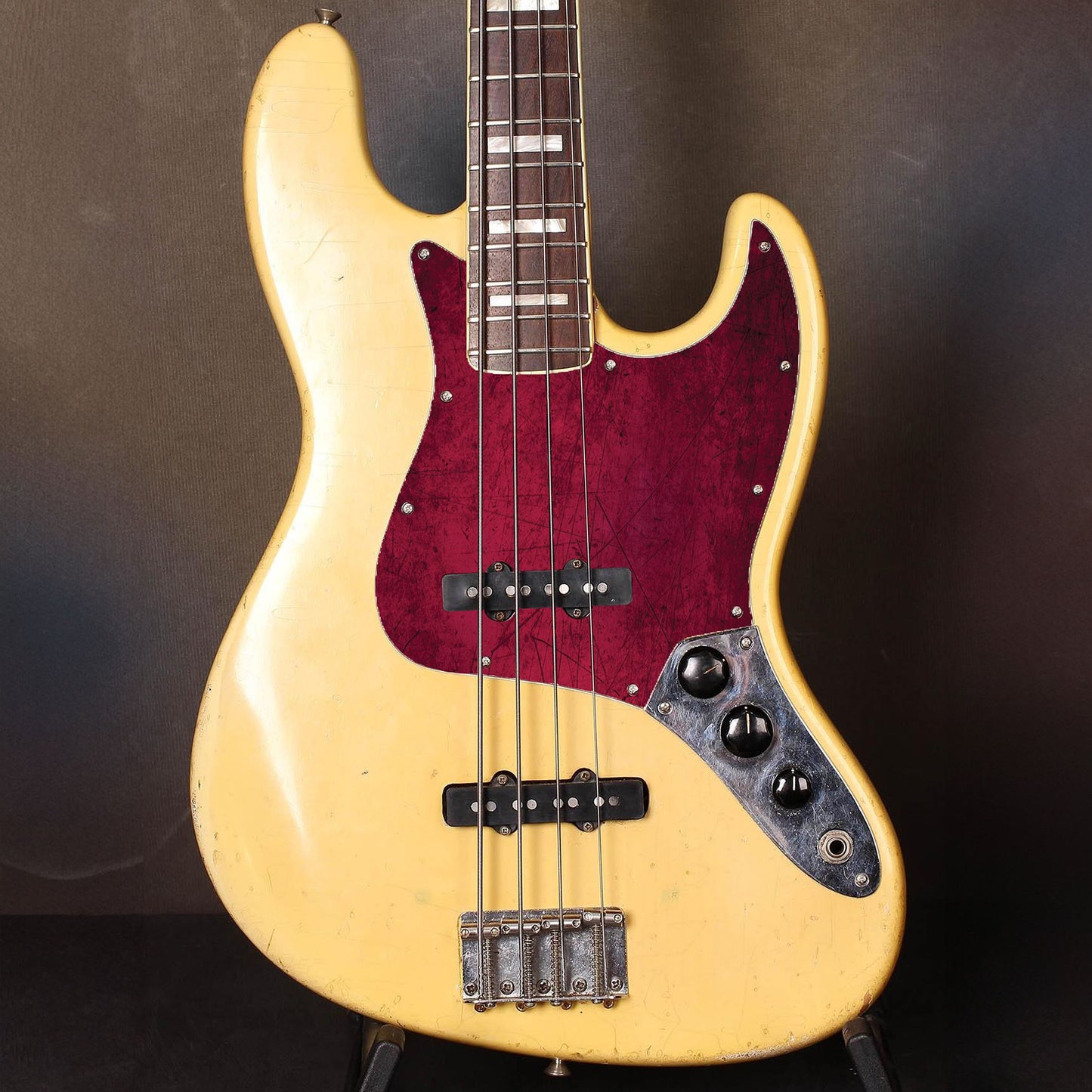 Egyedi Fender Jazz Bass gitár koptató élénk bordó árnyalatokkal, karcos felületi mintázattal és karakteres vintage megjelenéssel
