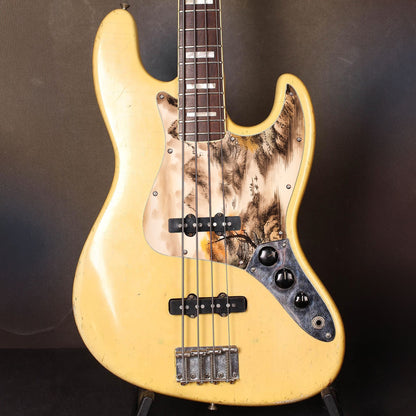 Egyedi Fender Jazz Bass gitár koptató tradicionális tájképpel, narancssárga lombú fával, hegyekkel és folyón evező csónakokkal