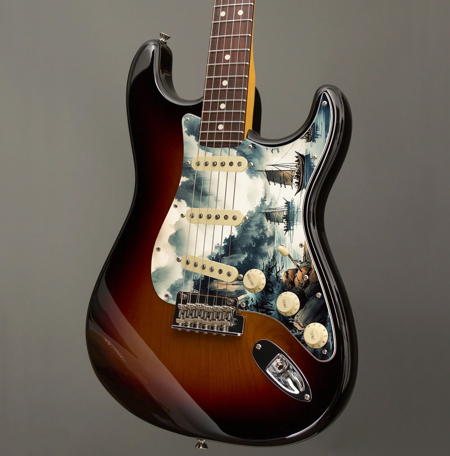 Egyedi Fender Stratocaster gitár koptató festői tájképpel, hegyekkel, fákkal és hagyományos vitorlás hajókkal a nyugodt vízen