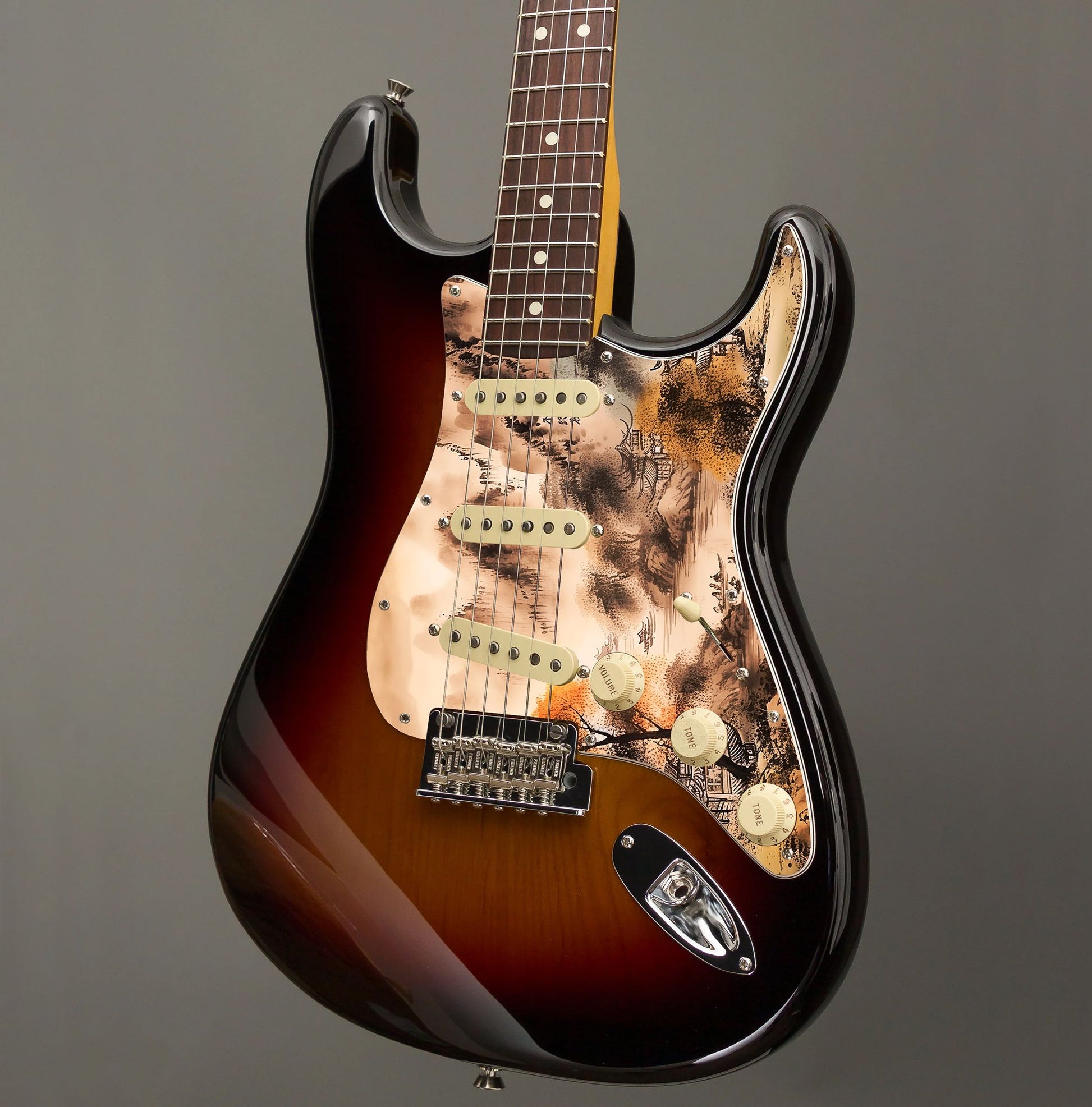 Egyedi Fender Stratocaster gitár koptató tradicionális tájképpel, narancssárga lombú fával, hegyekkel és folyón evező csónakokkal