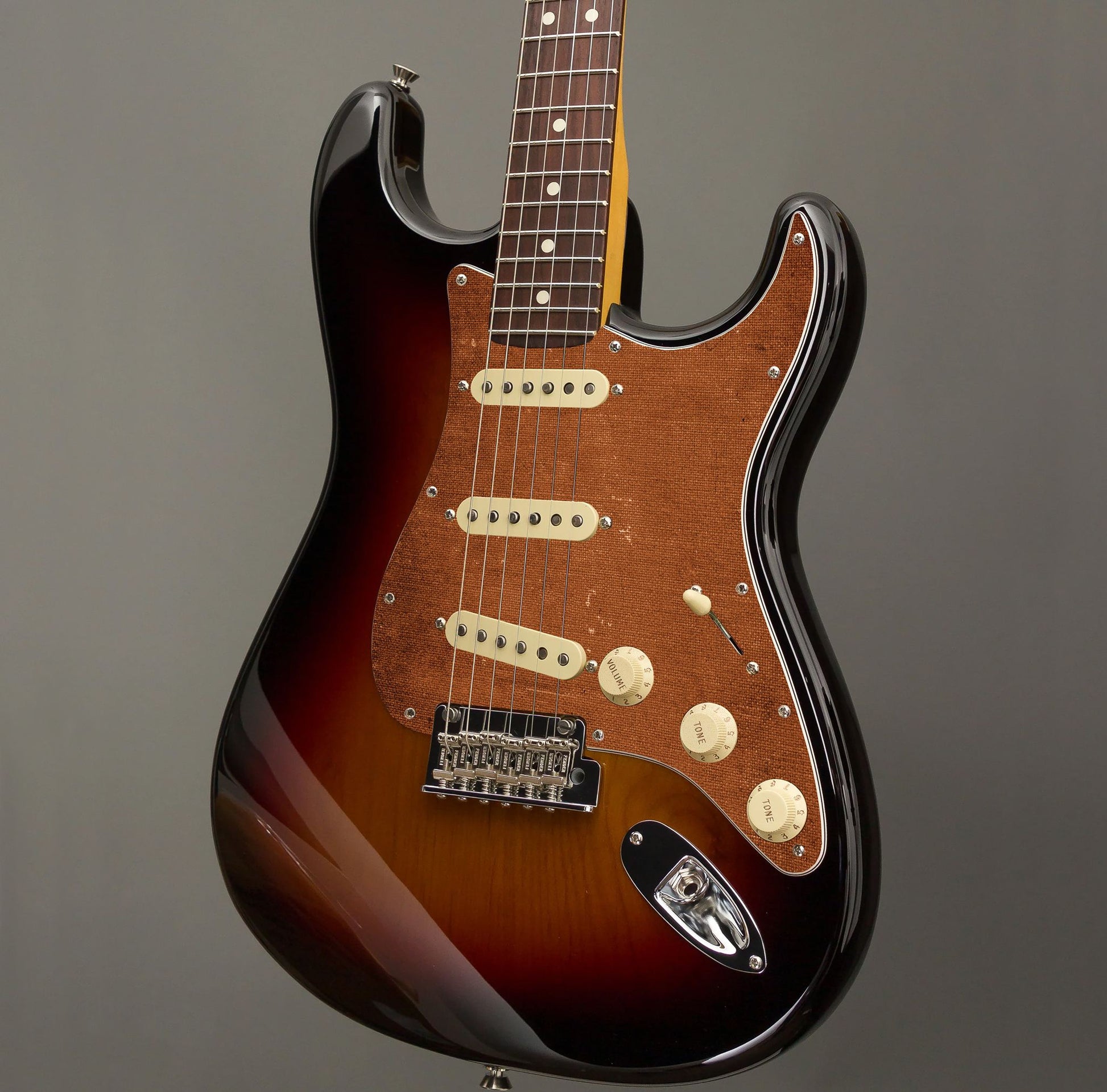 Egyedi Fender Stratocaster gitár koptató meleg barna vászonhatású textúrával, enyhén kopott felülettel és vintage stílusú részletekkel