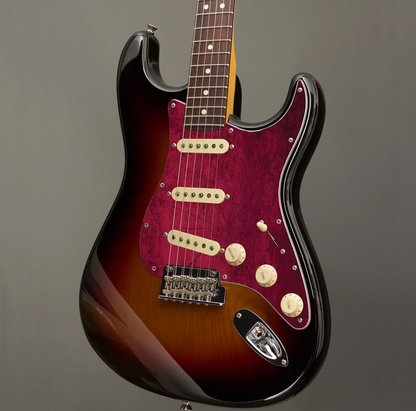 Egyedi Fender Stratocaster gitár koptató élénk bordó árnyalatokkal, karcos felületi mintázattal és karakteres vintage megjelenéssel