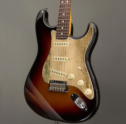 Egyedi Fender Stratocaster gitár koptató kopott arany tónusokkal, zöldes oxidációs mintázattal és matt textúrával